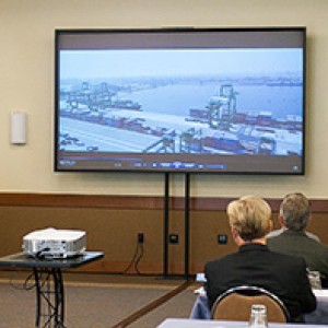 Delegates and business briefing attendees watch informational video about L&T Shipbuilding, Ltd. at the Kattupalli Port in Chennai