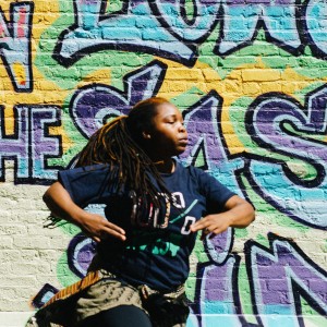 Jemima Angulu from Nigeria dances in front of a mural in NYC